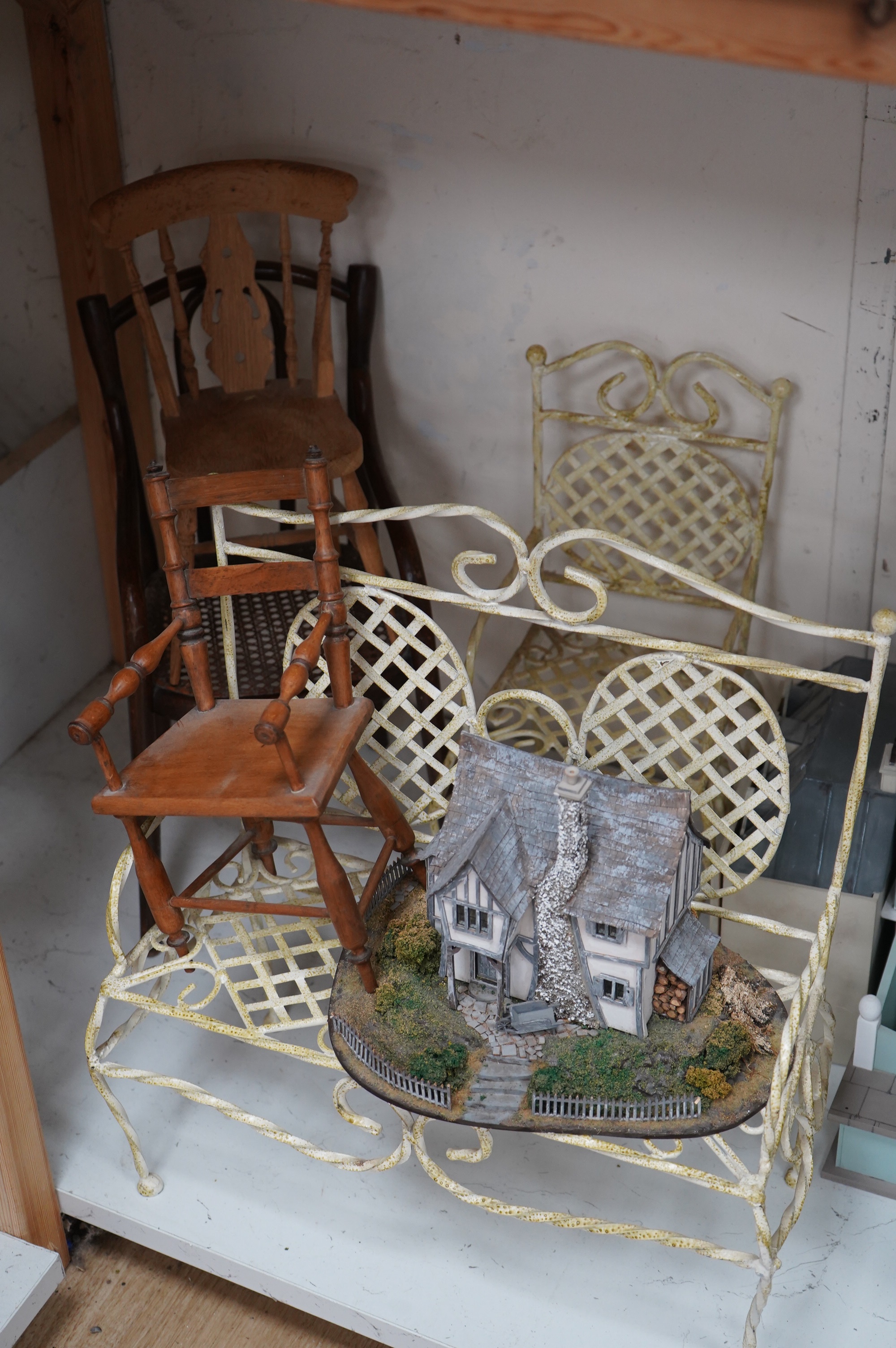 A modern plywood slot together model of a chateau, 50cm high, together with six miniature doll’s houses, a miniature wrought iron garden bench and chair set, and three miniature wooden chairs. Condition - fair.